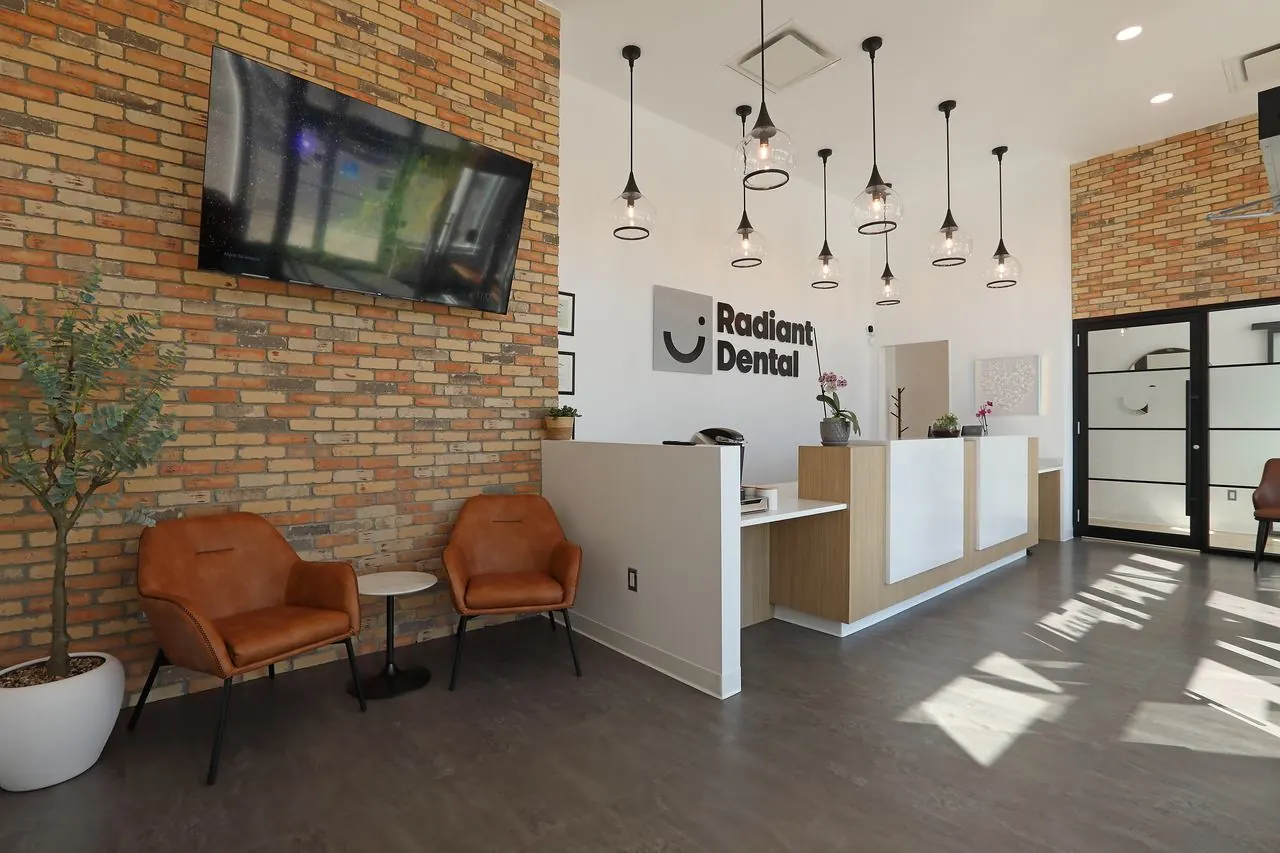 The lounge at Radiant Dental with leather chairs and an exposed brick wall